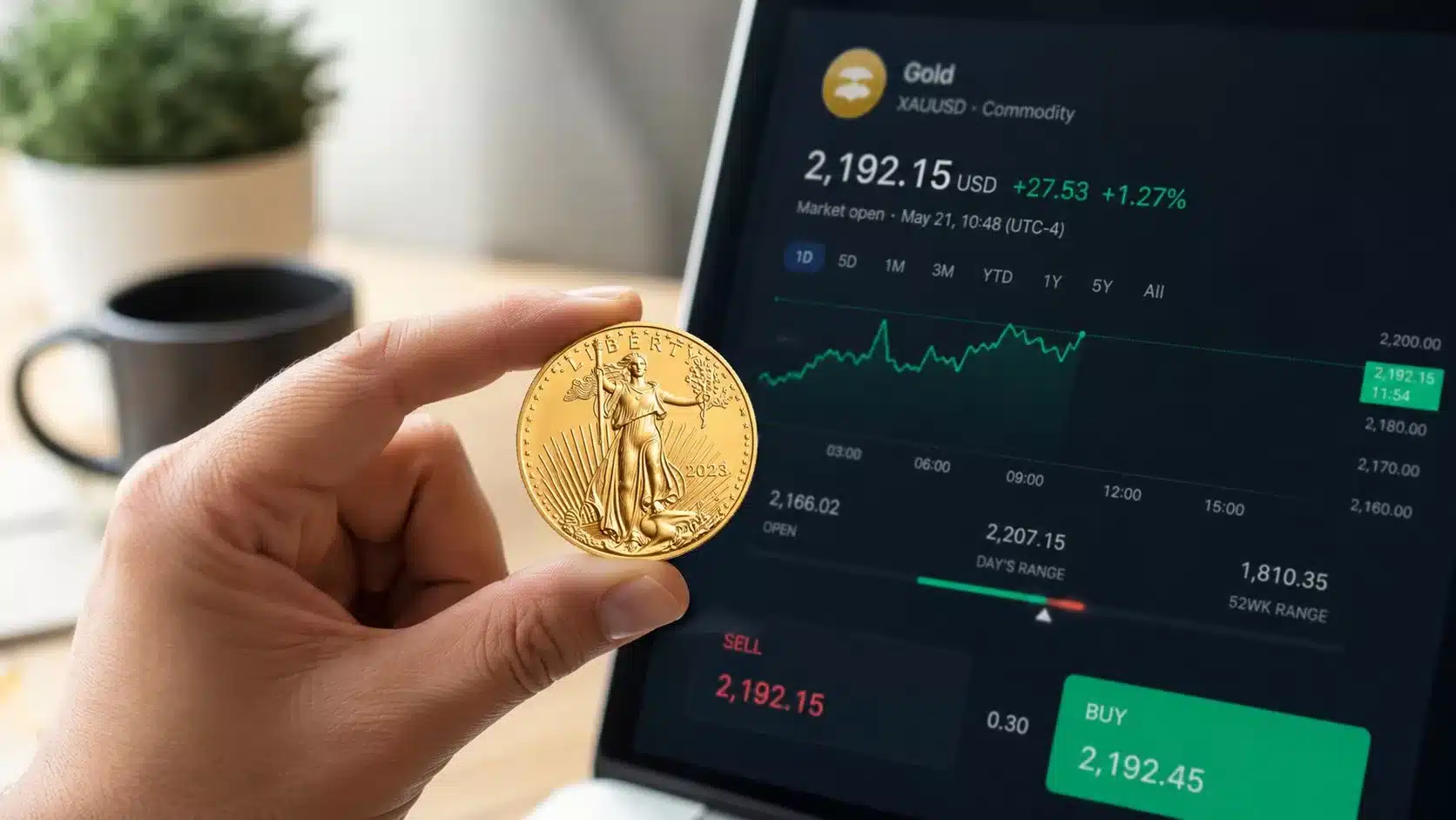 A hand holding a 2023 1 oz gold eagle coin in front of a laptop showing gold market prices.